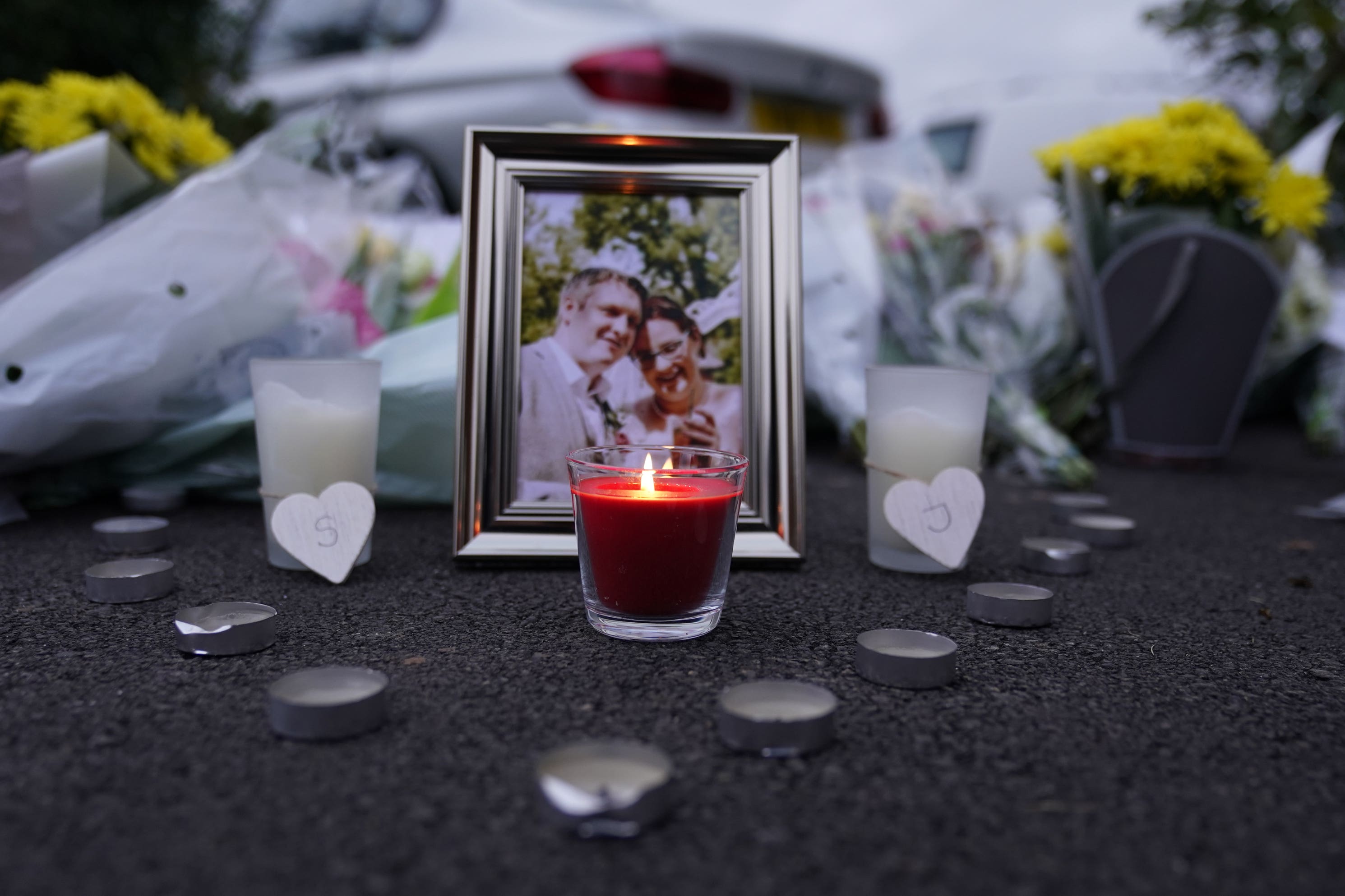 A lit candle and picture frame next to floral tributes left near the scene in Norton Fitzwarren (Andrew Matthews/PA)