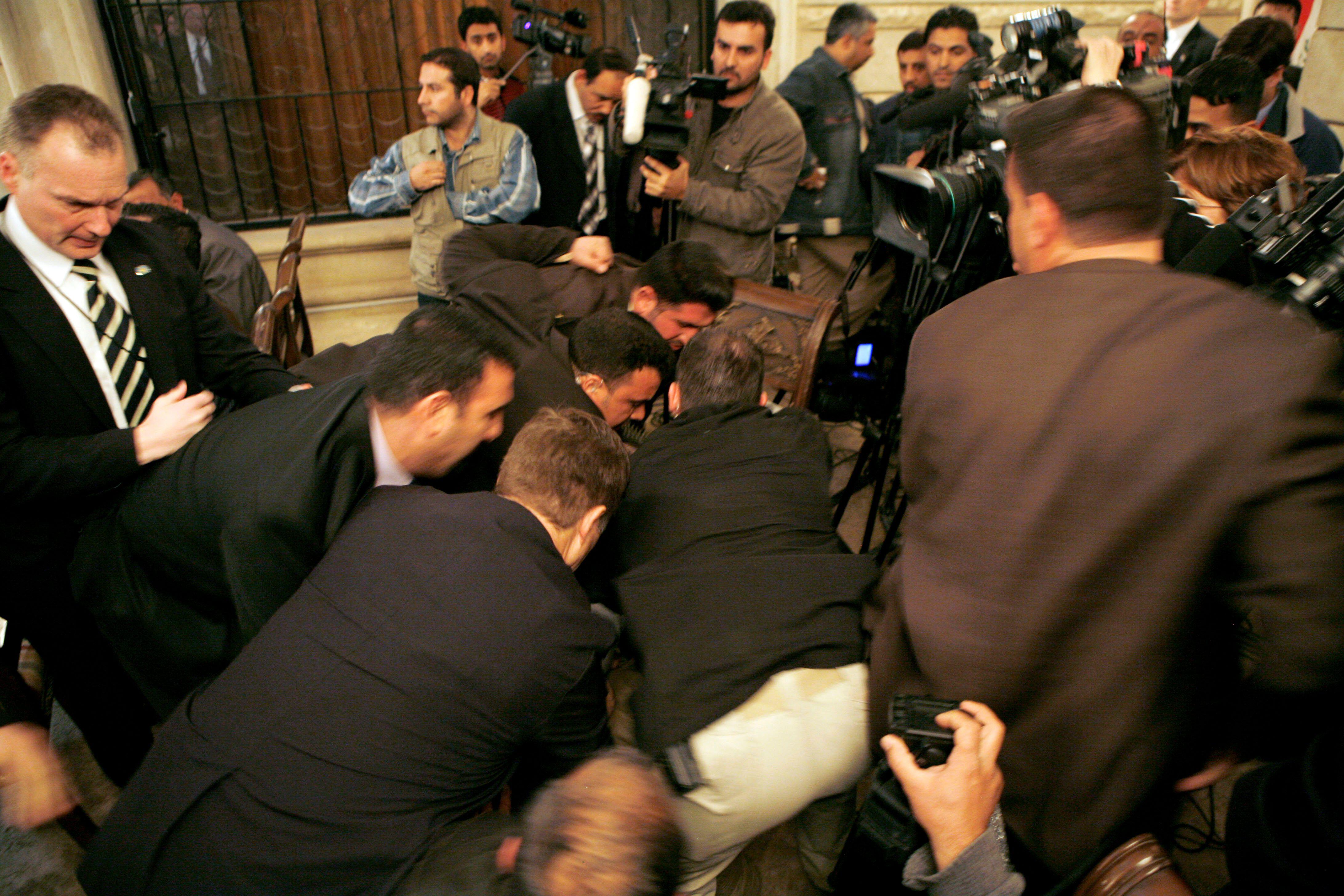 Security personnel tackle Muntadhar al Zaidi who threw a shoe at US President George W Bush