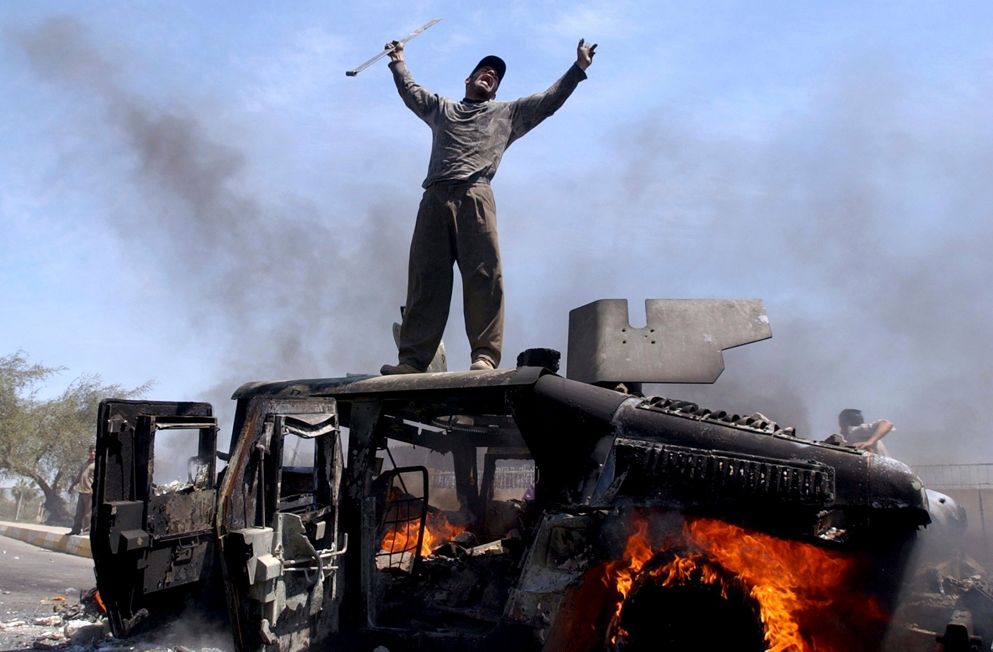An Iraqi man celebrates atop of a burning US Army Humvee in Baghdad, April 2004