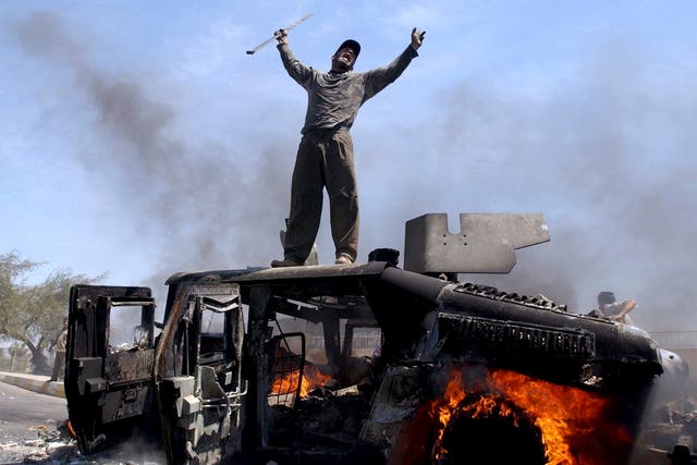 <p>An Iraqi man celebrates atop of a burning US Army Humvee in Baghdad, April 2004</p>