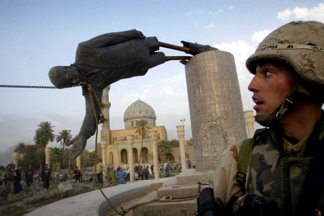<p>A US marine watches as the statue of Saddam Hussein falls in central Baghdad's Firdaus Square, 9 April, 2003</p>