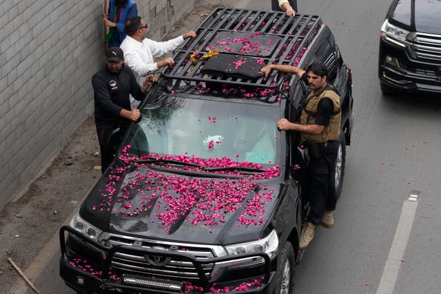 <p>Security personnel climb on a vehicle carrying former prime minister Imran Khan as it moves toward Islamabad at a road in Lahore, Pakistan, 18 March 2023</p>