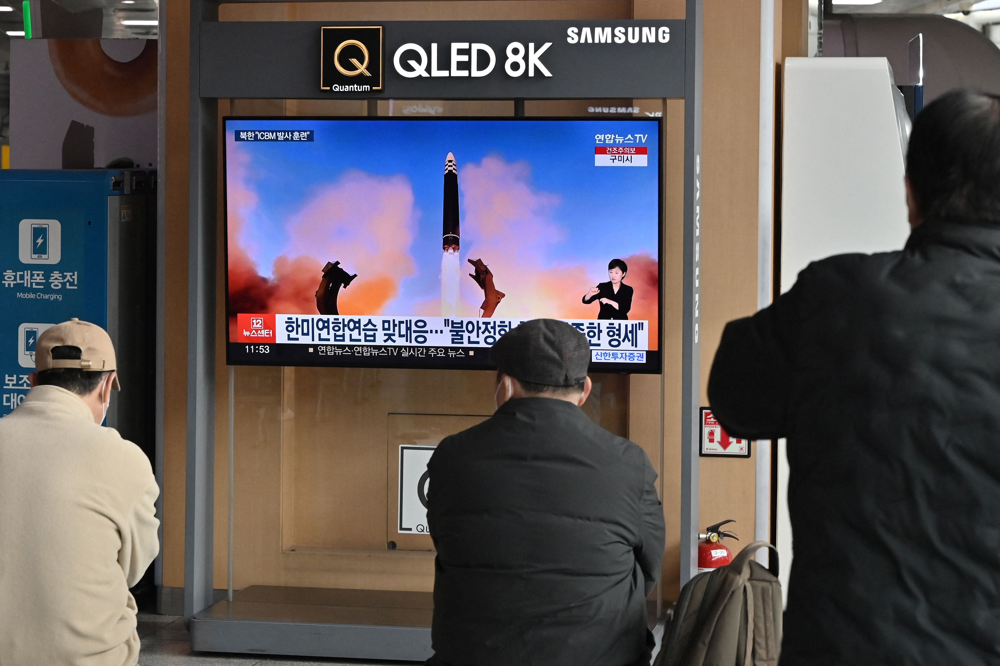 People watch a television news screen showing a picture of North Korea’s recent test-firing of a Hwasong-17 intercontinental ballistic missile (ICBM), at a railway station in Seoul