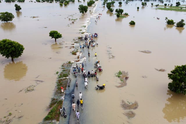 <p>People walk through floodwaters after heavy rainfall in Hadeja, Nigeria, Sept 19, 2022. The UN climate science report, due to be published on Monday, has been delayed by a fight between rich and poor countries over the text </p>