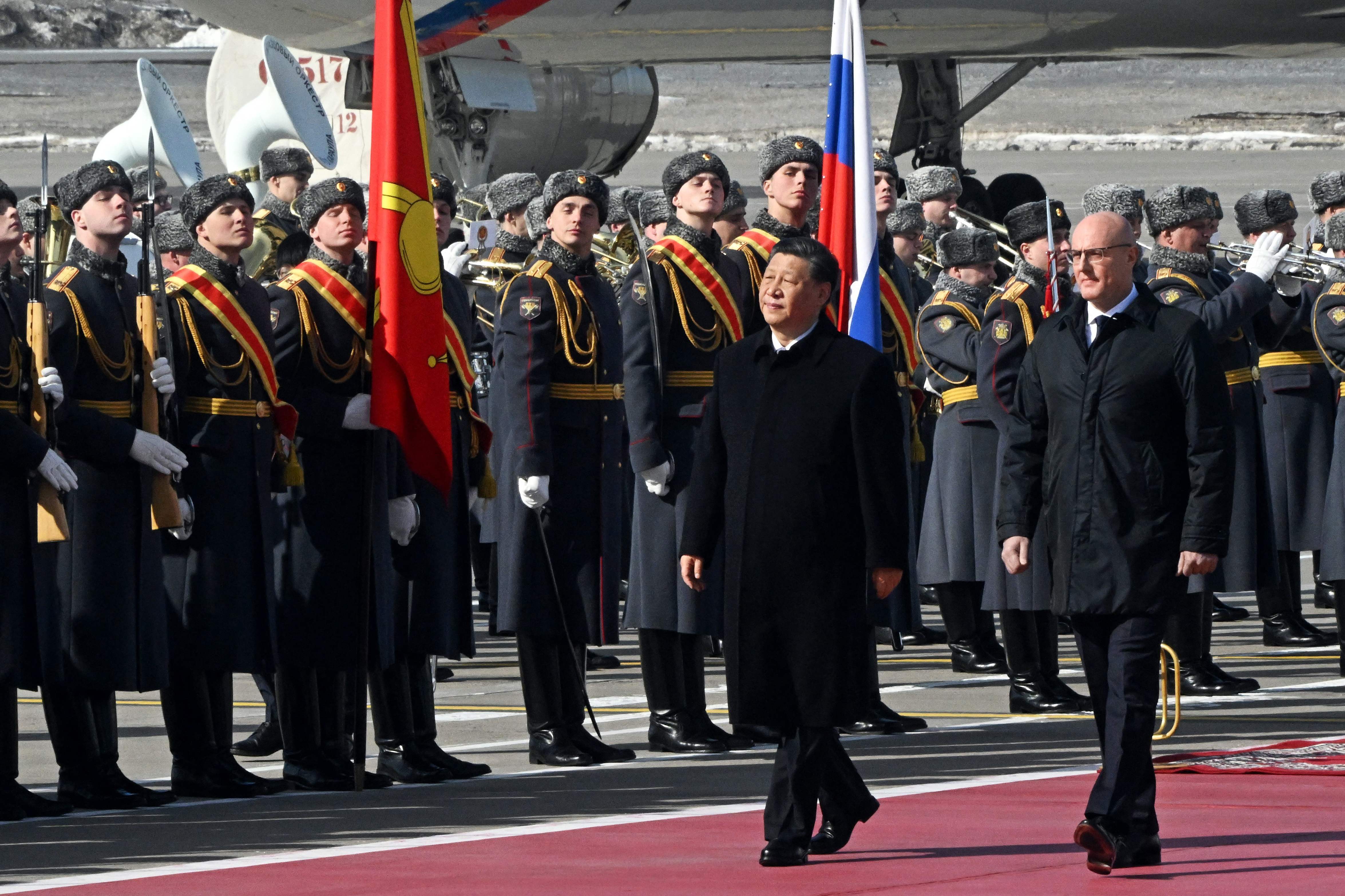 China's President Xi Jinping, accompanied by Russian Deputy Prime Minister Dmitry Chernyshenko, walks past honour guards during a welcoming ceremony at Moscow's Vnukovo airport