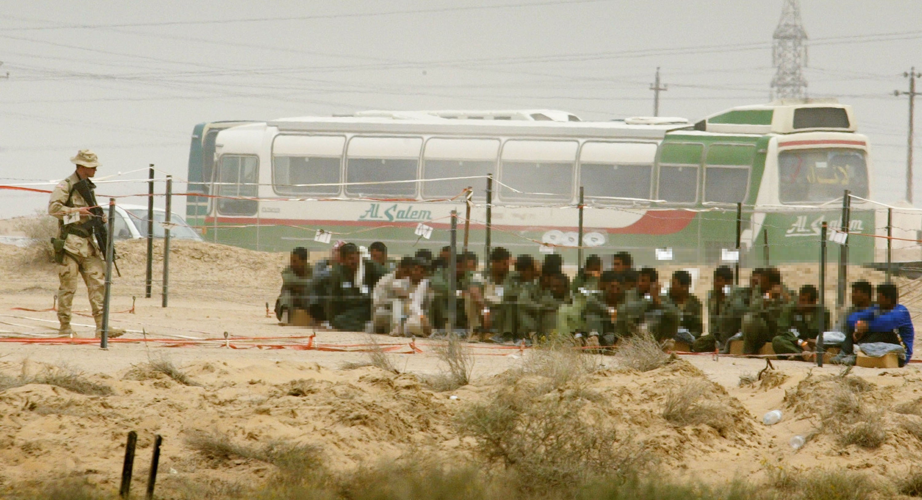 A soldier stands guard over prisoners of war at Camp Bucca on 8 April, 2003