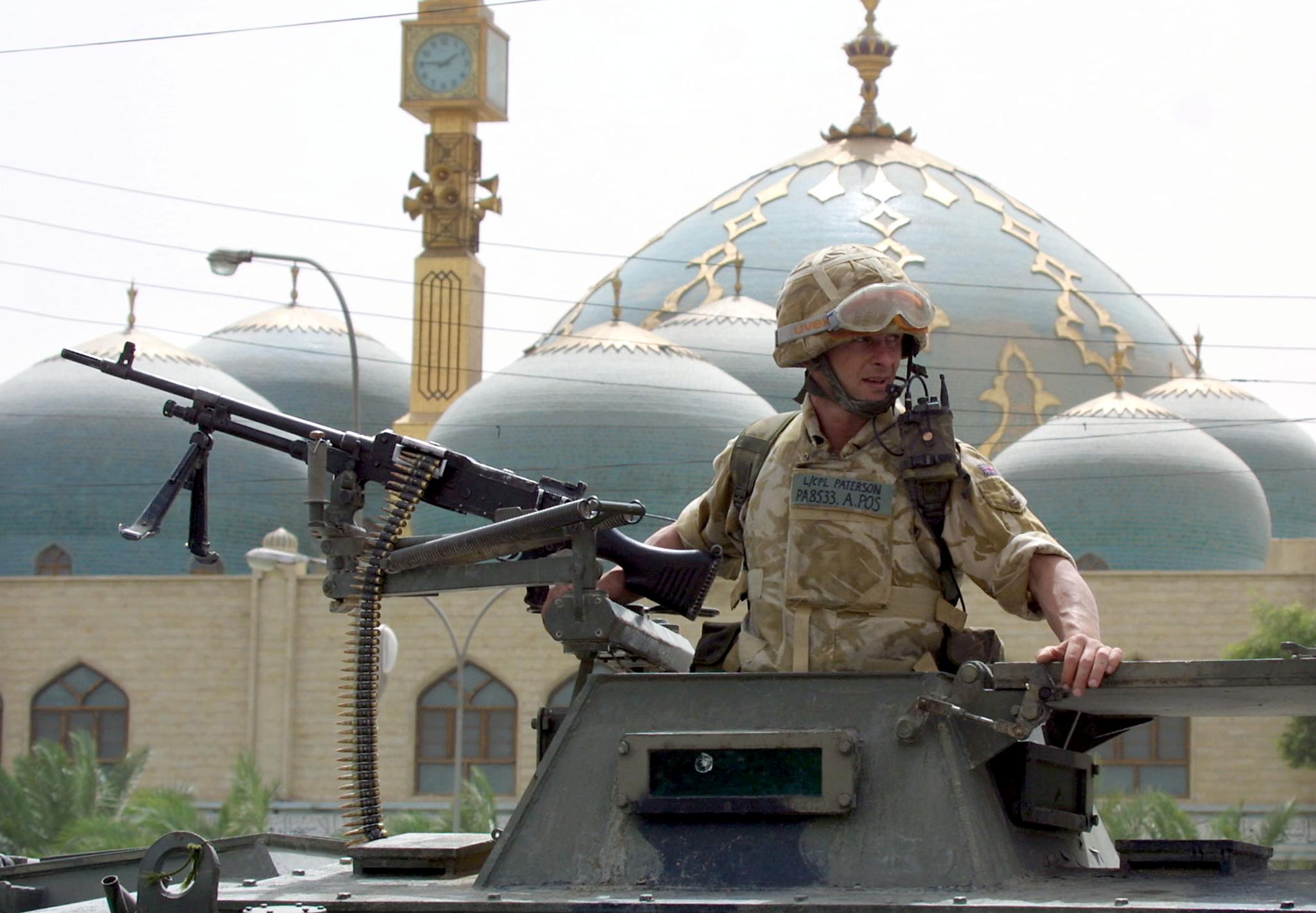 A British soldier patrols a street in front of a mosque in the southern Iraqi city of Basra on 13 September, 2003