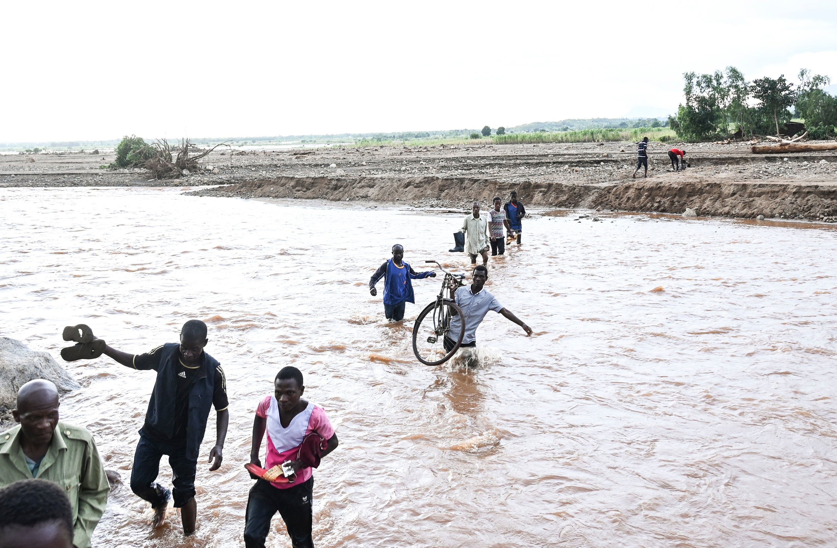 People wade through flood waters caused by last week's heavy rains caused by Tropical Cyclone Freddy in Phalombe, southern Malawi