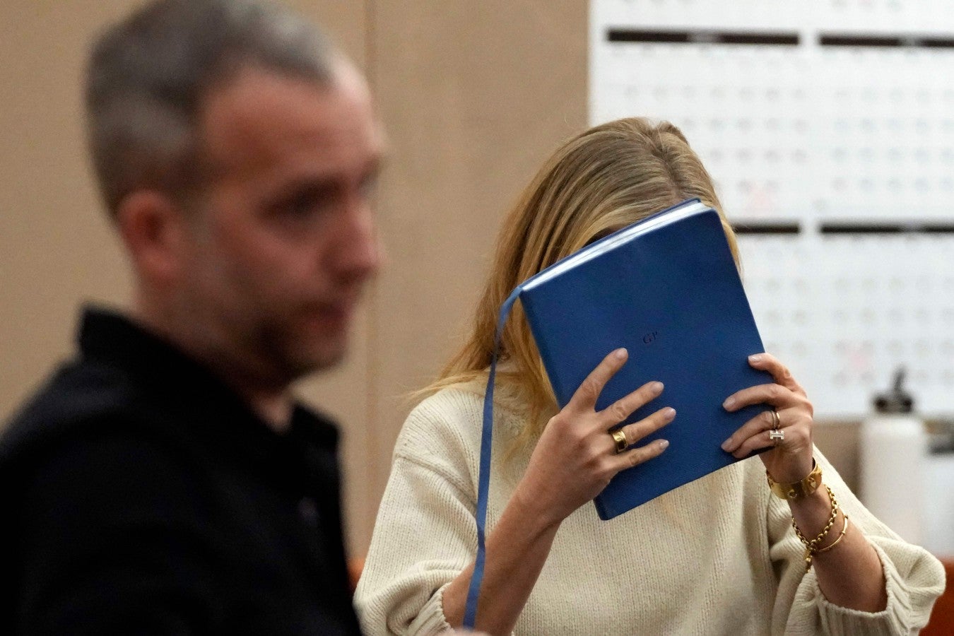 Ms Paltrow was seen hiding her face behind a blue notebook as she exited the room