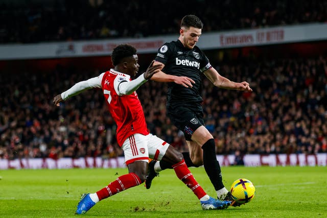 Arsenal’s Bukayo Saka and West Ham United’s Declan Rice battle for the ball during the Premier League match at the Emirates Stadium, London. Picture date: Monday December 26, 2022.