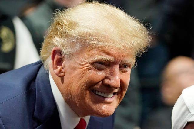 <p>Former president Donald J Trump smiles as he poses for a photo</p>