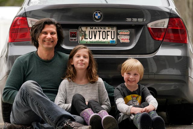<p>Peter Starostecki and his kids Sadie, center, and Jo Jo, pose behind their car with the vanity license plate that the state of Maine has deemed in appropriate, Wednesday, March 8, 2023, in Poland, Maine</p>