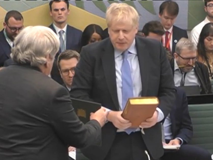 The Clerk to the Committee (left) administers the oath to Johnson