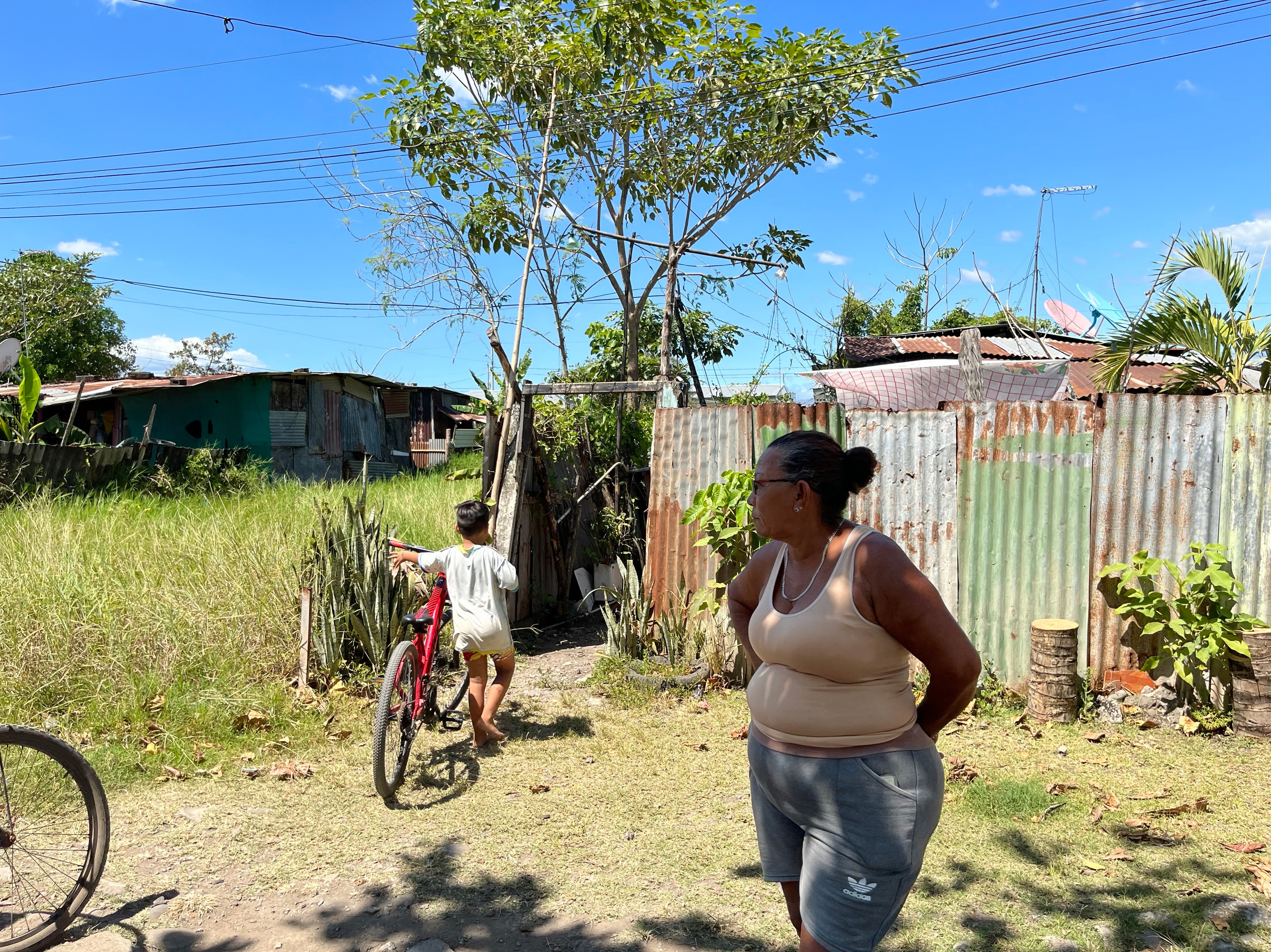 Maribel Sandi, a community activist, watches her grandson as he wheels his bicycle into her yard in Bella Vista