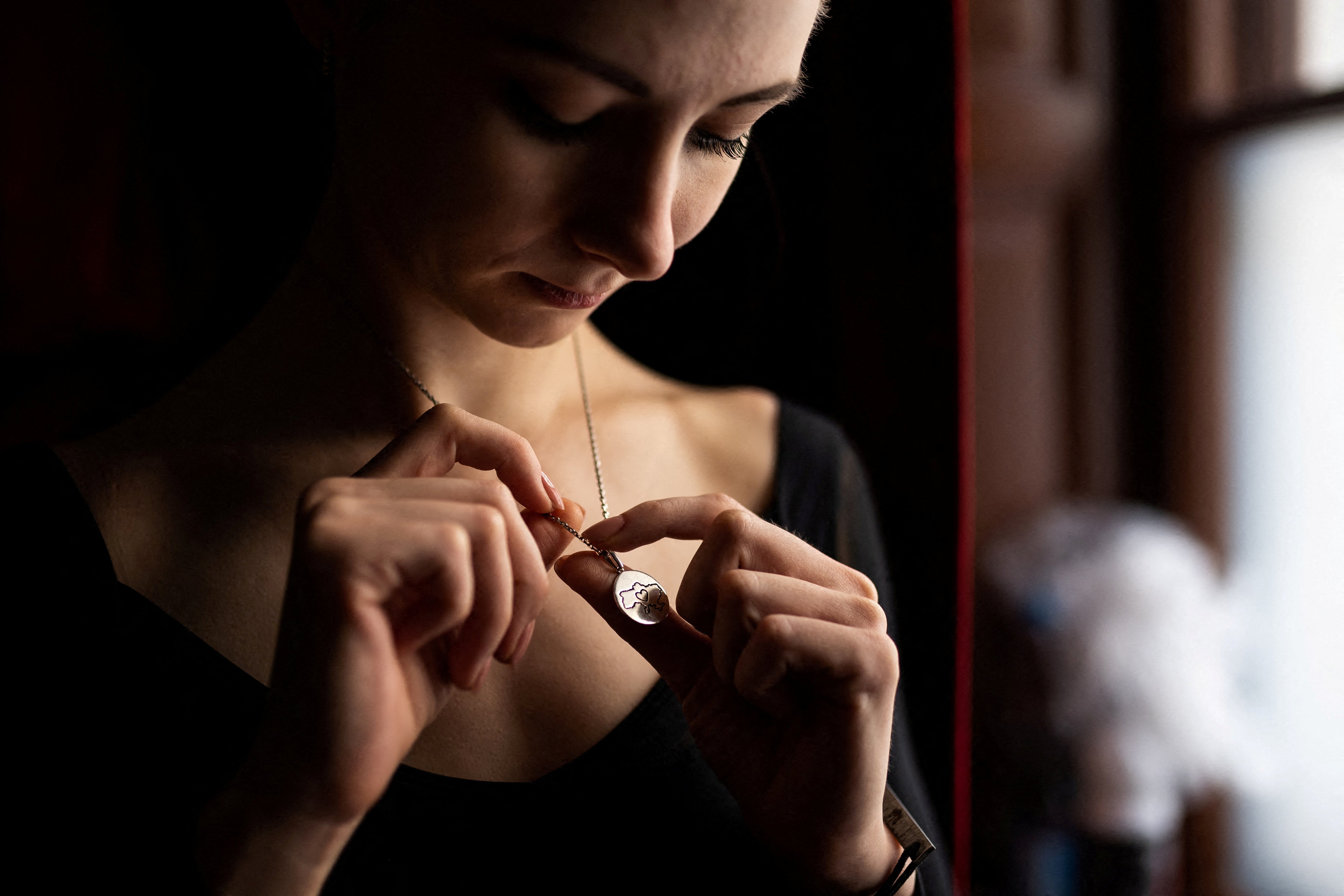 The dancer looks at her necklace, which is engraved with a map of her country, after a stage rehearsal