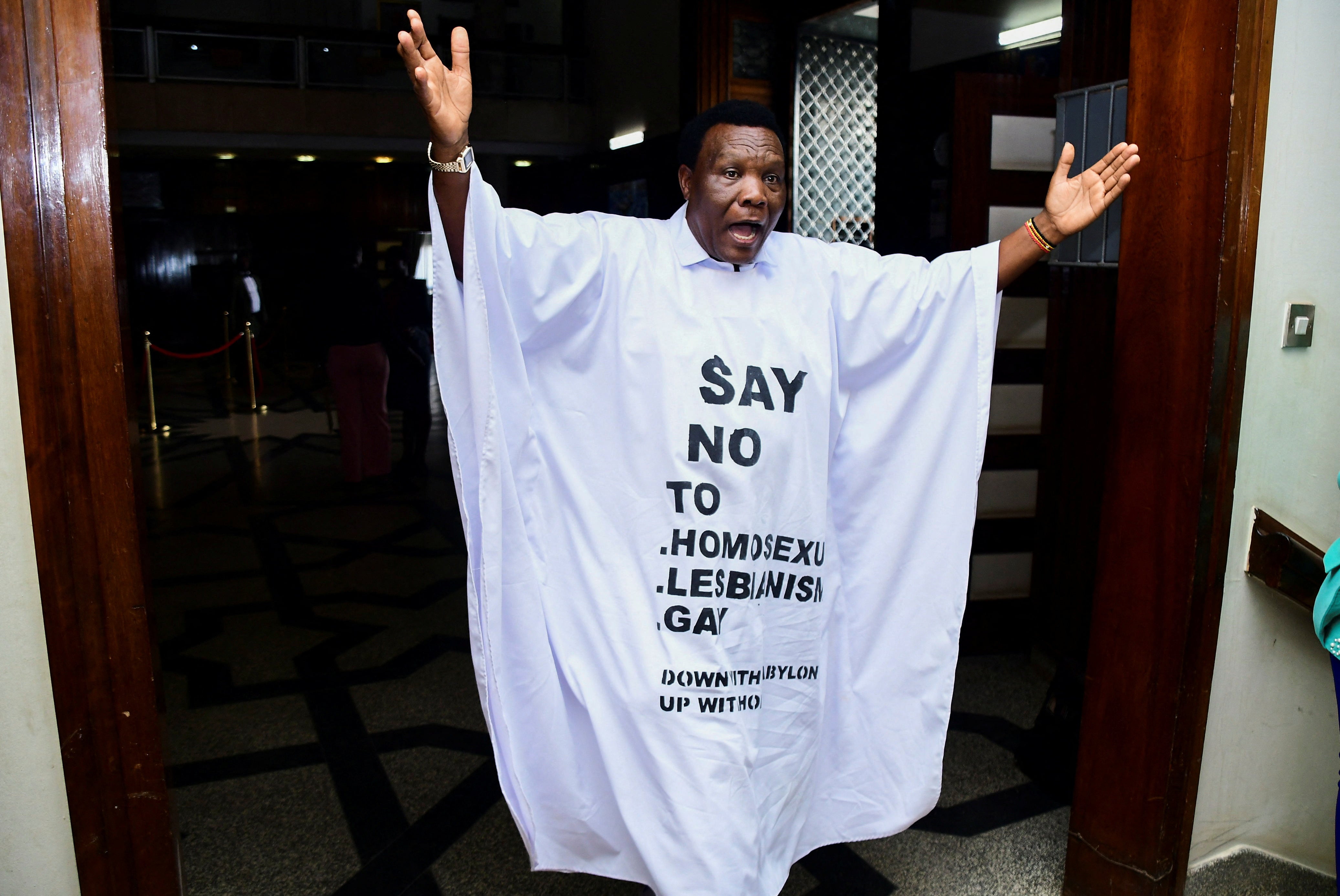 <p>Member of Parliament from Bubulo contituency John Musira dressed in an anti gay gown gestures as he leaves the chambers</p>