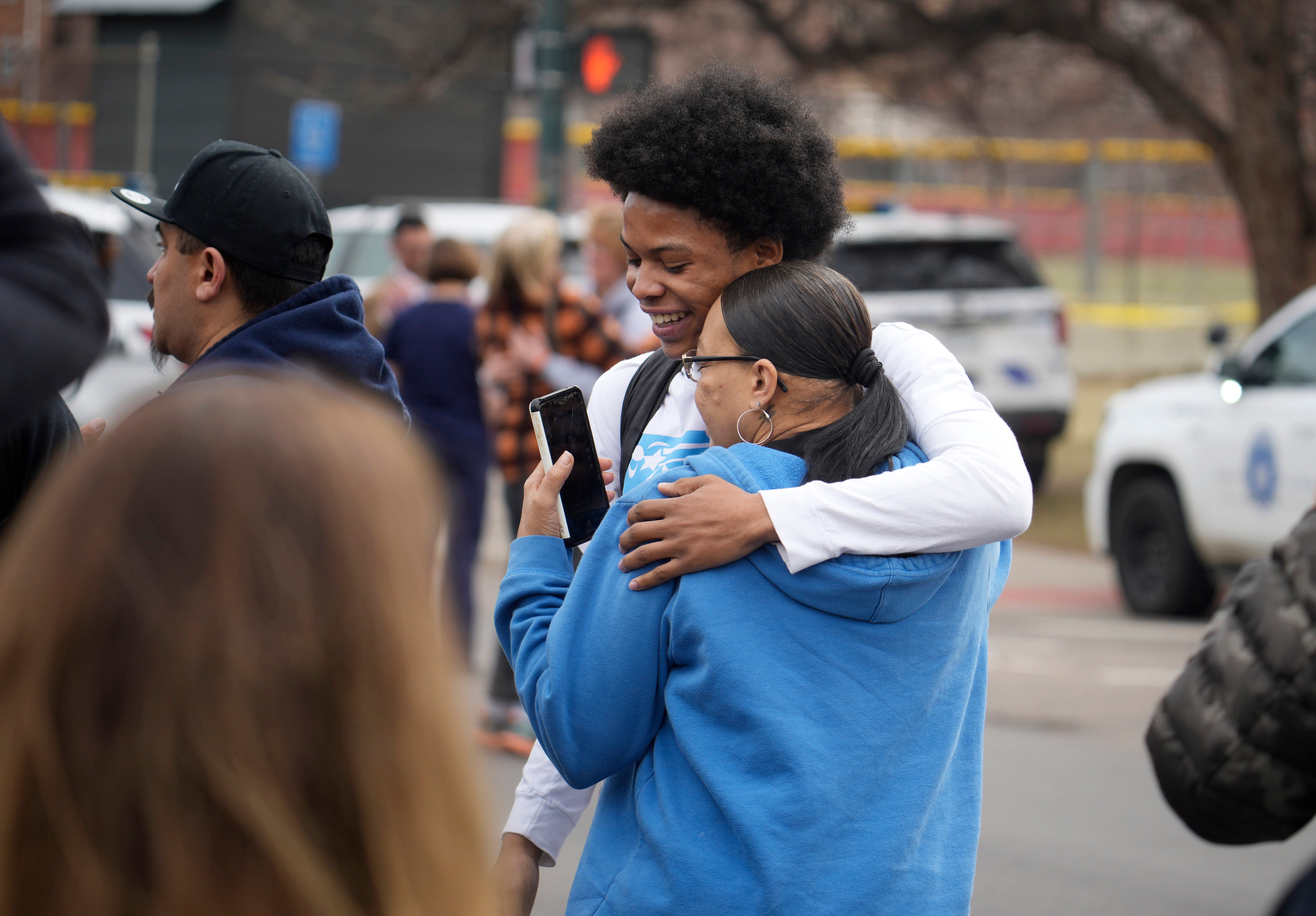 A student, rear, hugs a woman as they reunite following a shooting at East High School, Wednesday, March 22, 2023, in Denver