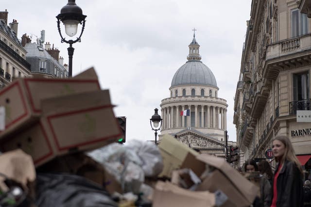 <p>A pedestrian walks past garbage bags that have been piling up near The Pantheon as waste collectors are on strike since 6 March to protest against the French government’s proposed pensions reform</p>