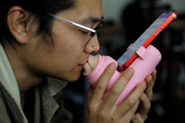 <p>Jing Zhiyuan uses a remote kissing device ‘Long Lost Touch’, as he demonstrates for camera how to use it </p>