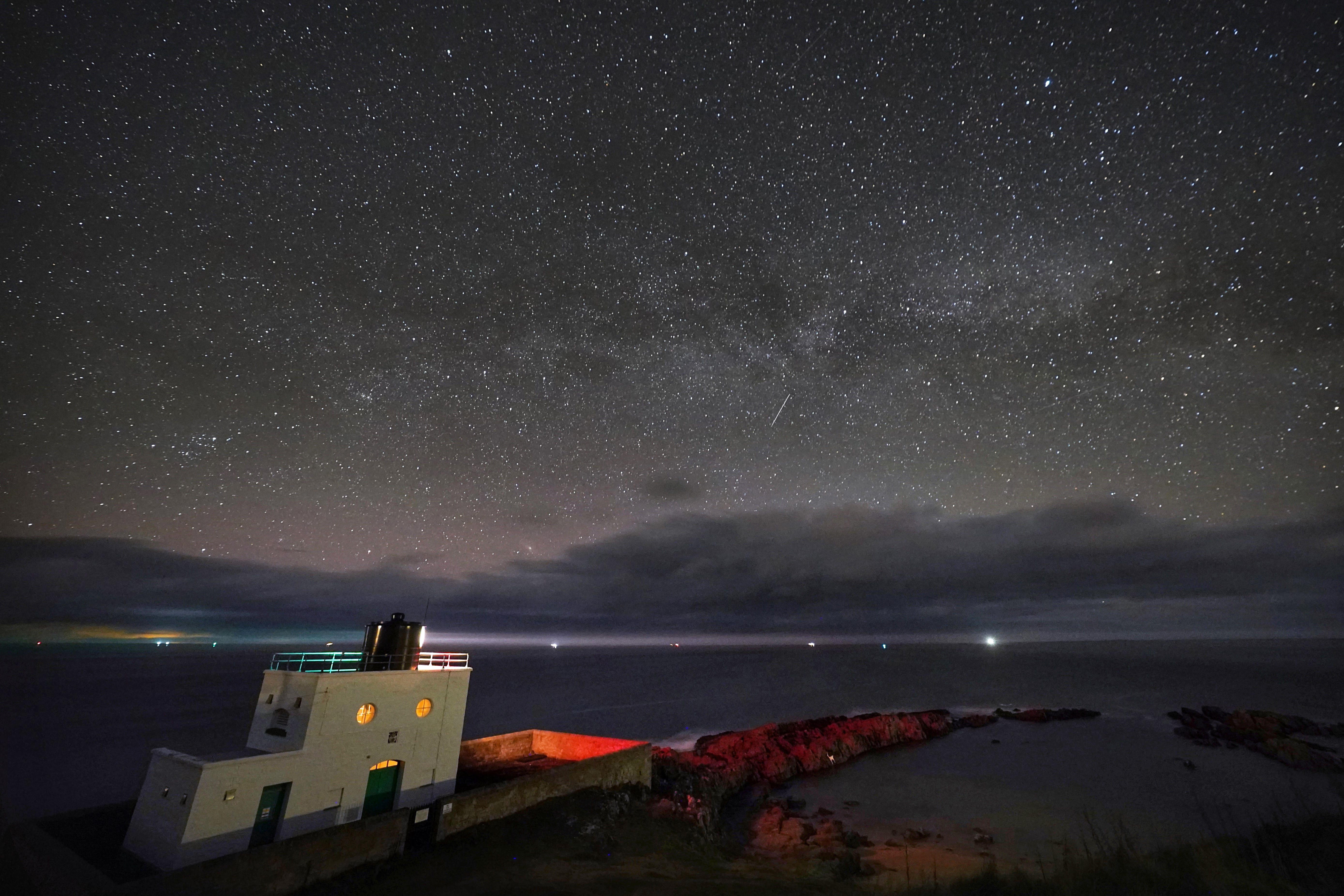 The Milky Way core rises at 3am over Bamburgh Lighthouse in Northumberland on the North East (Owen Humphreys/PA)