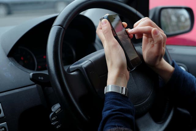 Nearly all hand-held use of a mobile phone while driving on Britain’s roads was made illegal in legislation implemented in March last year (Alamy/PA)