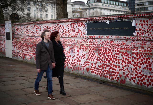 <p>People walk past messages written on the National Covid Memorial Wall on the third anniversary of the United Kingdom going into a national lockdown</p>