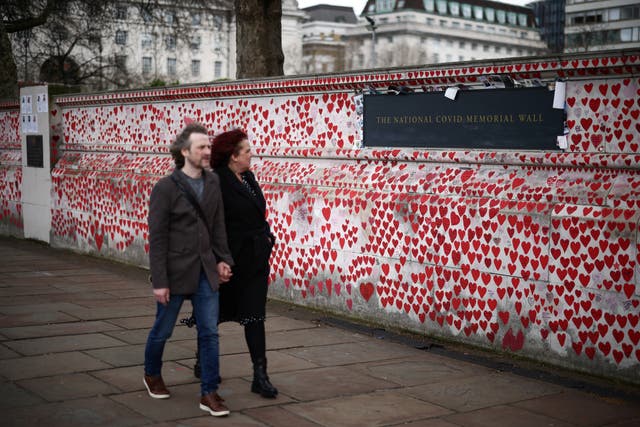 La gente pasa junto a los mensajes escritos en el Muro Conmemorativo Nacional de Covid, en el tercer aniversario del cierre nacional del Reino Unido