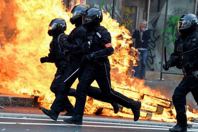 <p>French riot police run past a fire during a demonstration in Paris on Thursday</p>