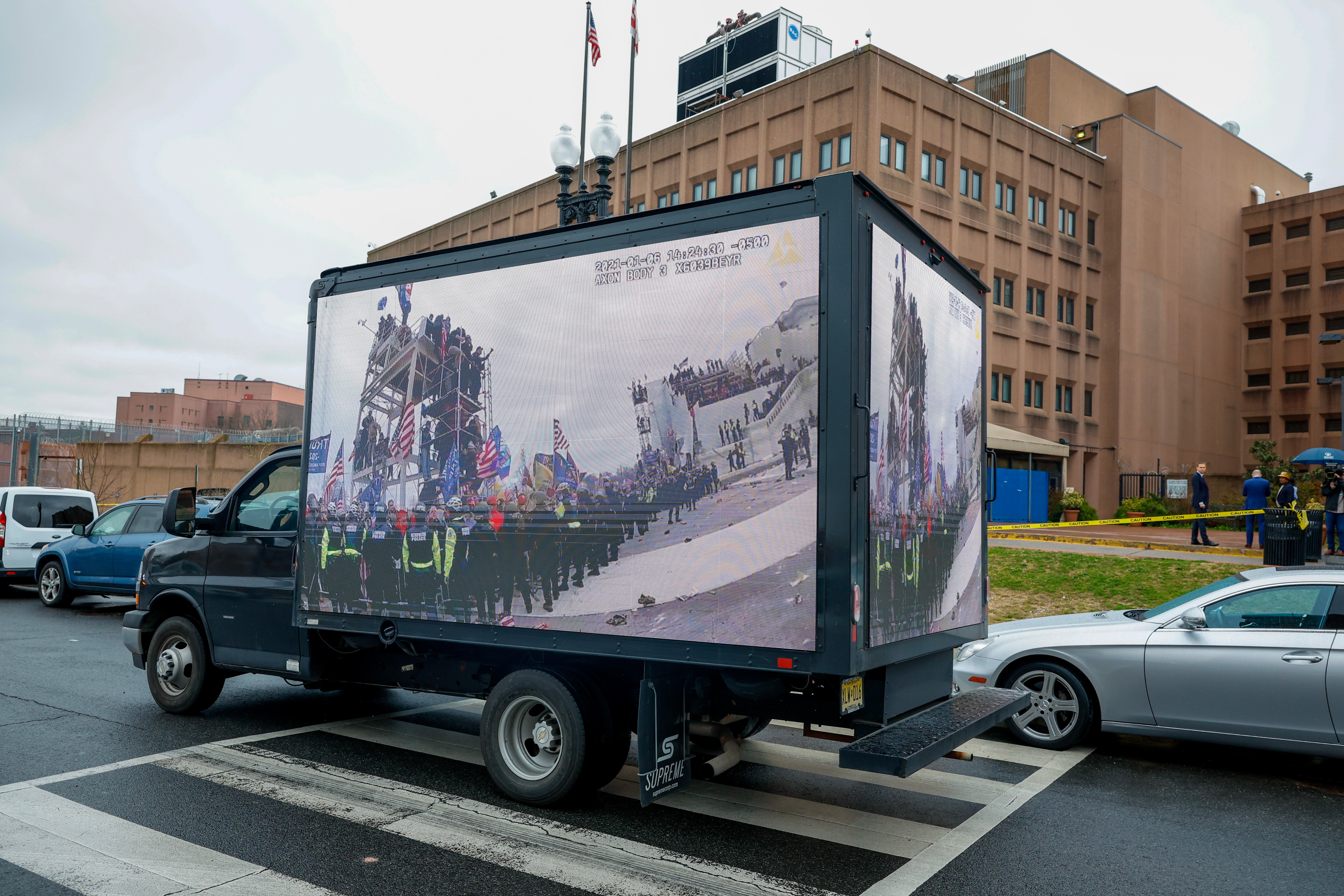 Footage of the January 6 riot is screened on the side of a truck outside the jail