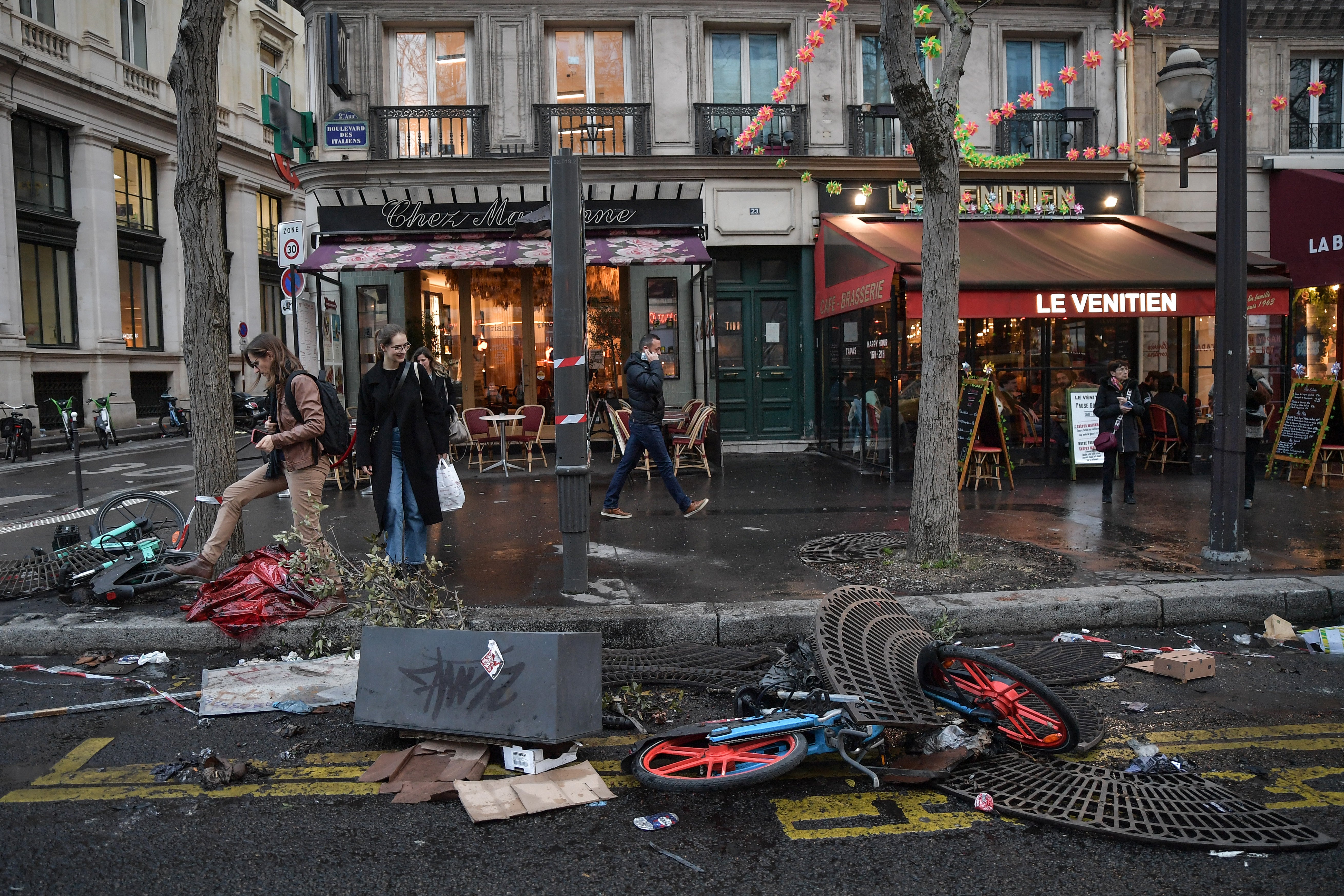 Pedestrians walk past damaged local properties after yesterday’s protests against the pensions reform in Paris