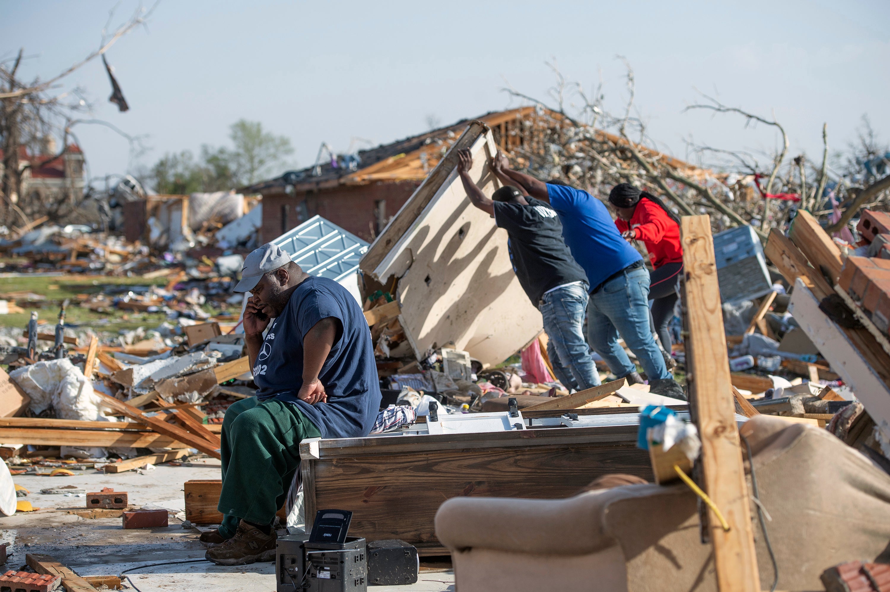 Wendell Sturdevant, of Rolling Fork, Miss., calls his wife as friends and his niece search through the rubble of what was a Blue Front Apartments duplex unit that he and his mother lived in