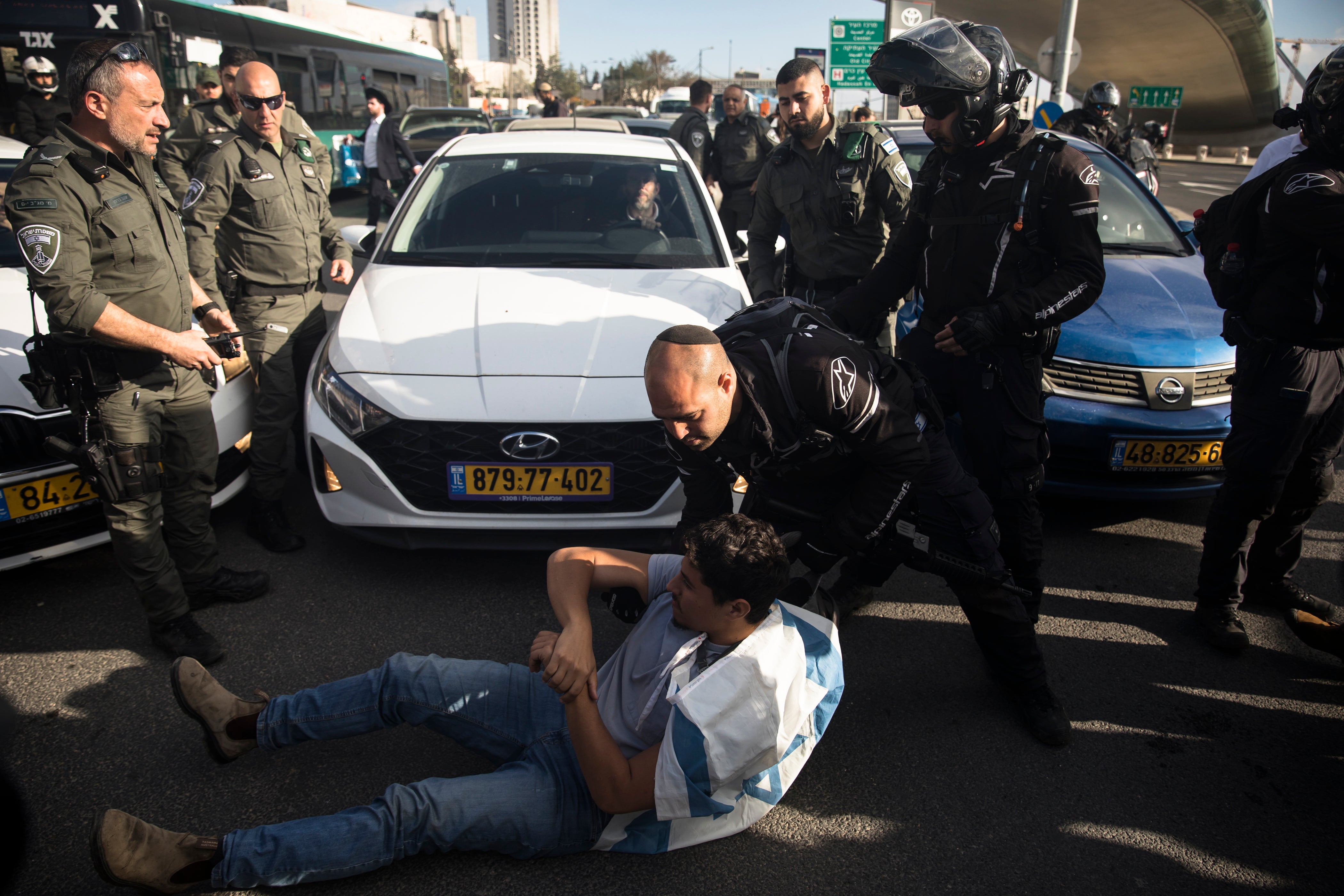 <p>Israeli police officers remove a protester blocking a main road</p>