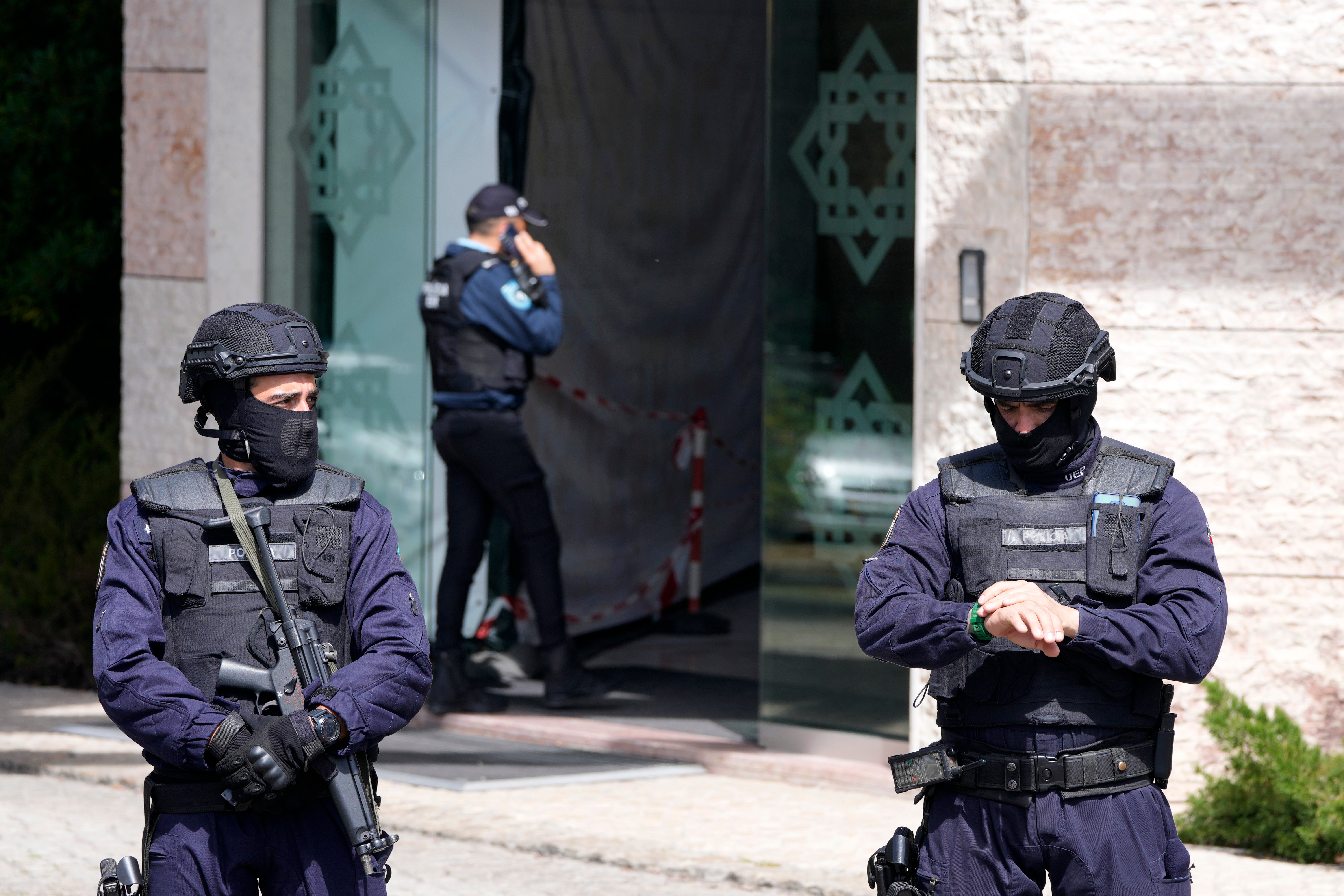 Police officers stand at the entrance of an Ismaili Muslim center in Lisbon, Portugal on Tuesday