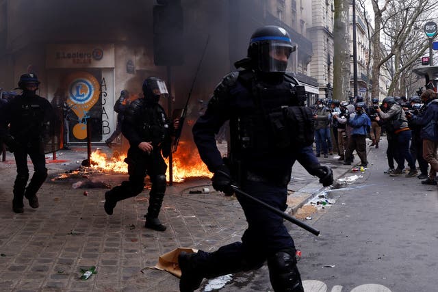 <p>French riot police run past a fire during clashes in Paris</p>
