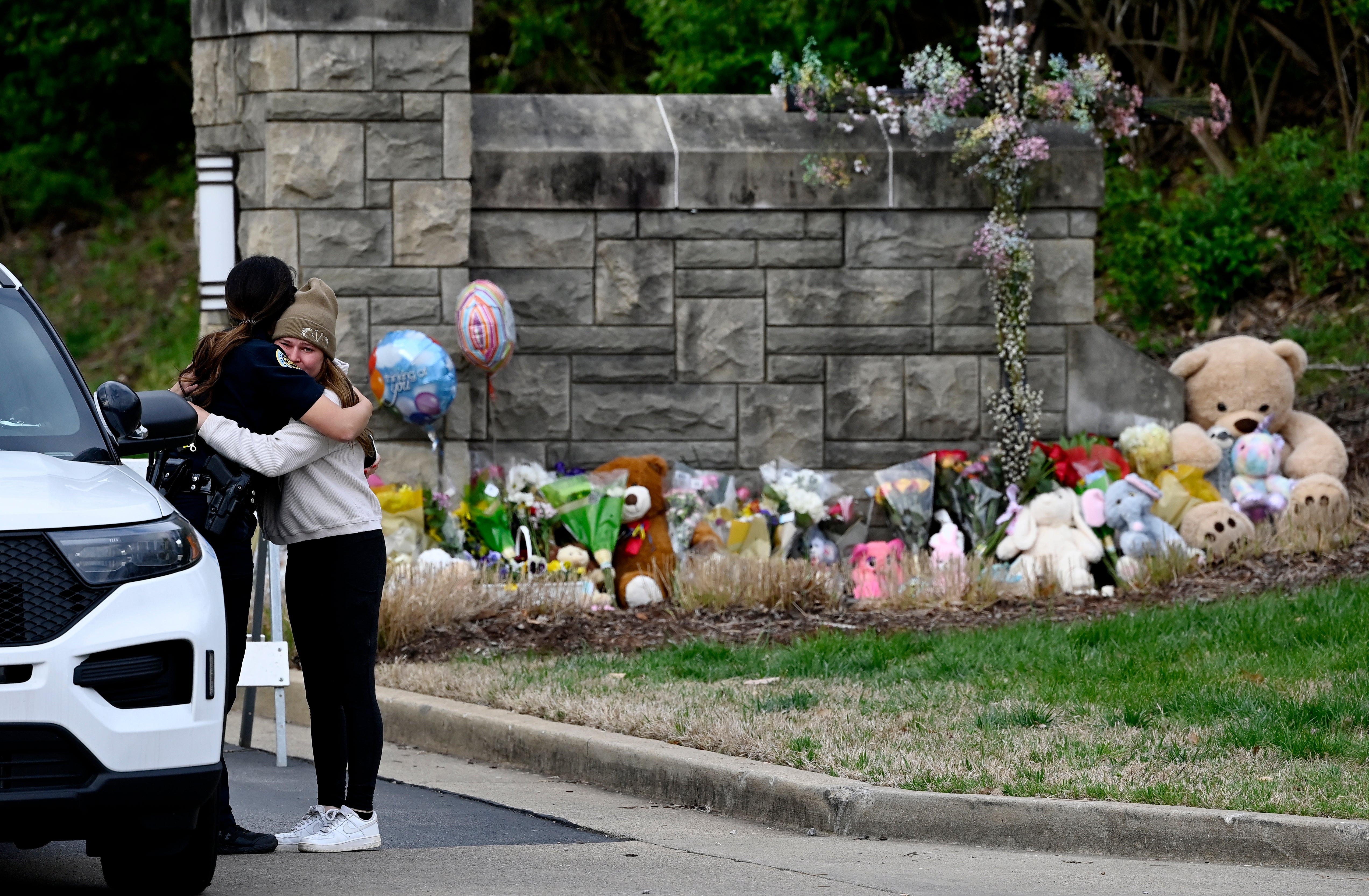 Ivy Huesmann hugs Metro Nashville police officer Angeline Comilla before visiting the makeshift memorial at the entrance to the Covenant School