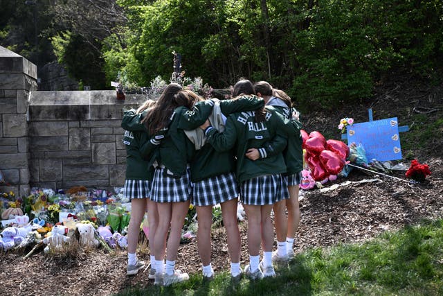 <p>Girls embrace in front of a makeshift memorial for victims by the Covenant School building at the Covenant Presbyterian Church following a shooting, in Nashville, Tennessee, March 28, 2023</p>