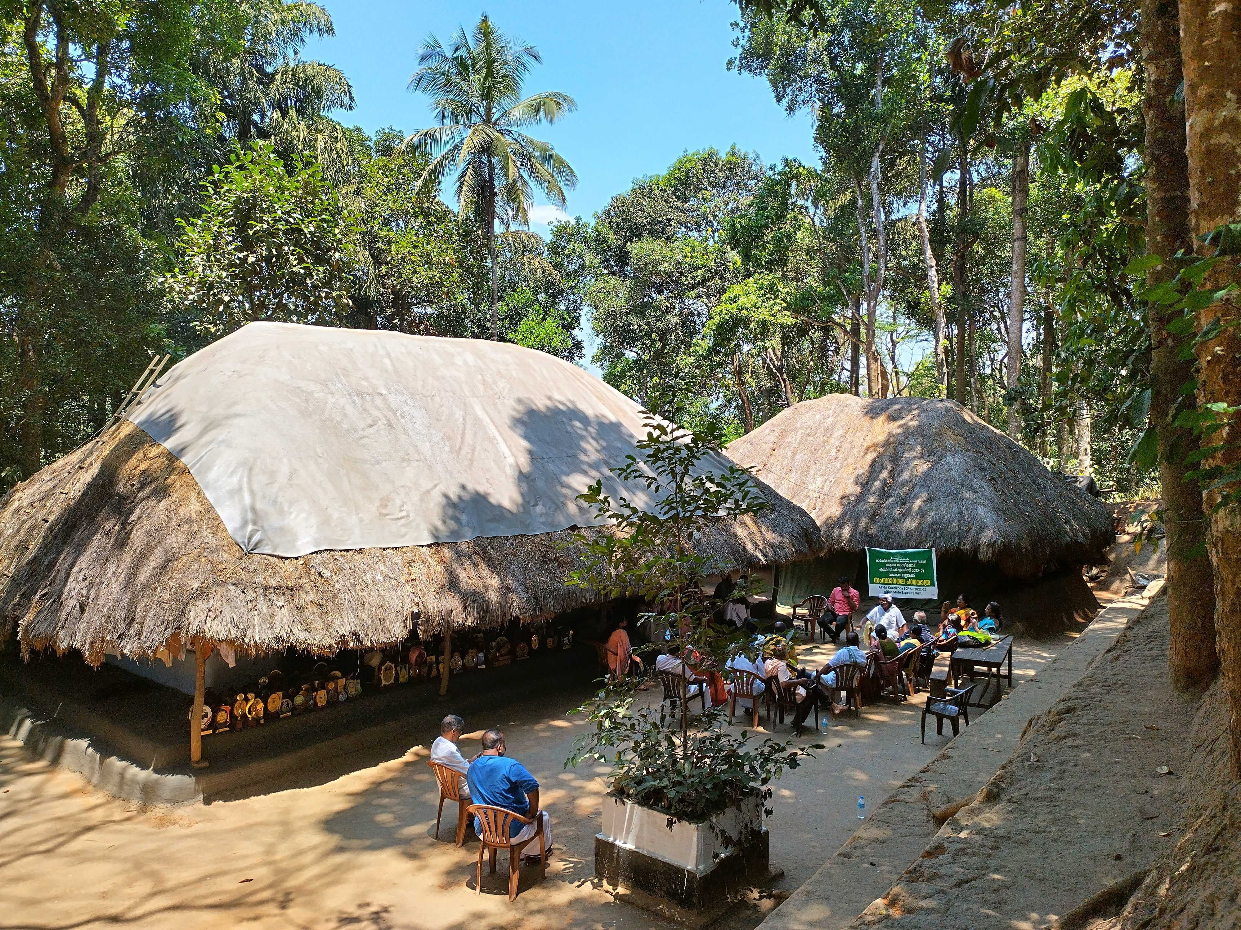 Padma Shri award-winner and tribal leader Cheruvayal Raman (in white) surrounded by his supporters seen at his house in Mananthavady in Wayanad. Dozens of trophies won by him are seen placed in the shade of his mud house