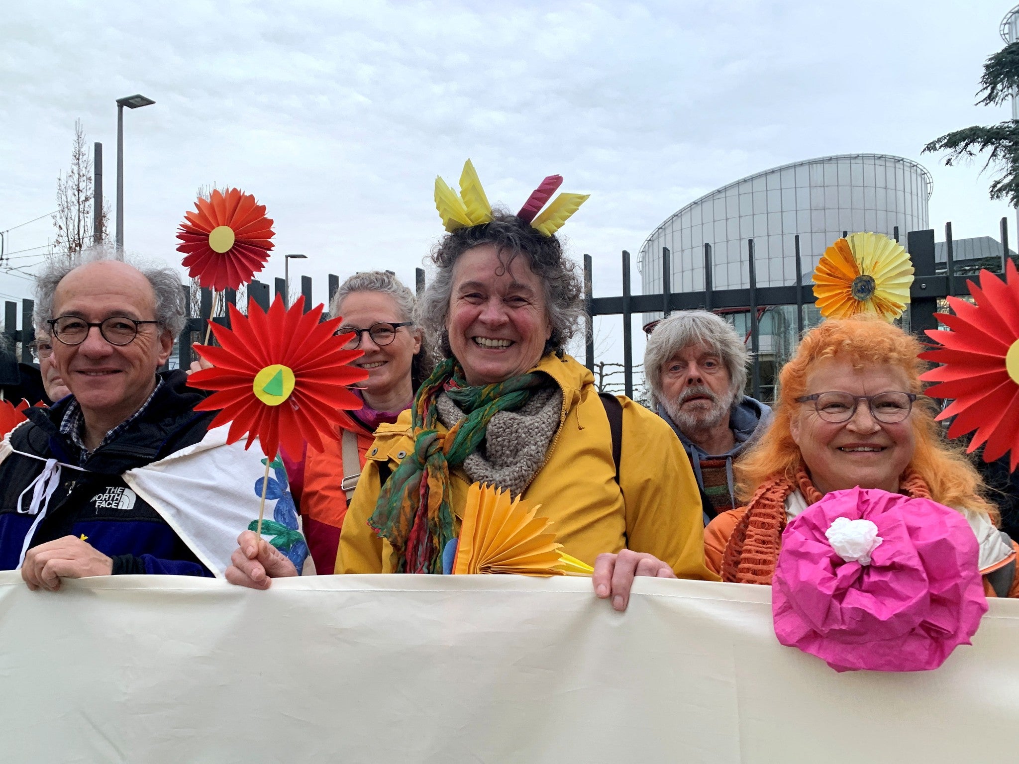 Supporters of the Senior Women for Climate Protection association hold paper flowers and a banner outside the European Court of Human Rights in Strasbourg