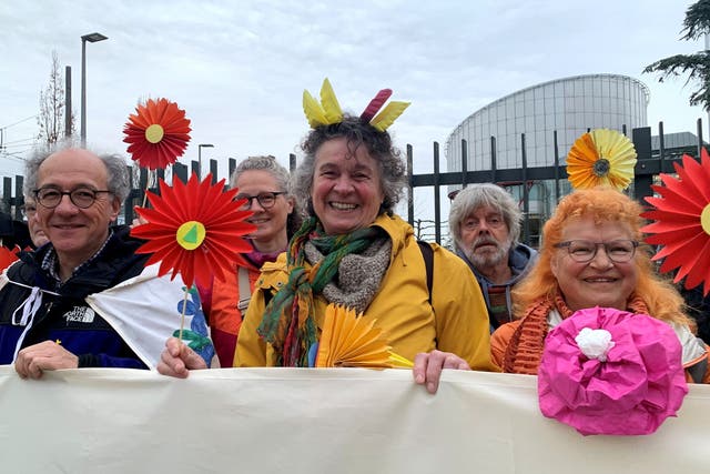 <p>Supporters of the Senior Women for Climate Protection association hold paper flowers and a banner outside the European Court of Human Rights in Strasbourg</p>