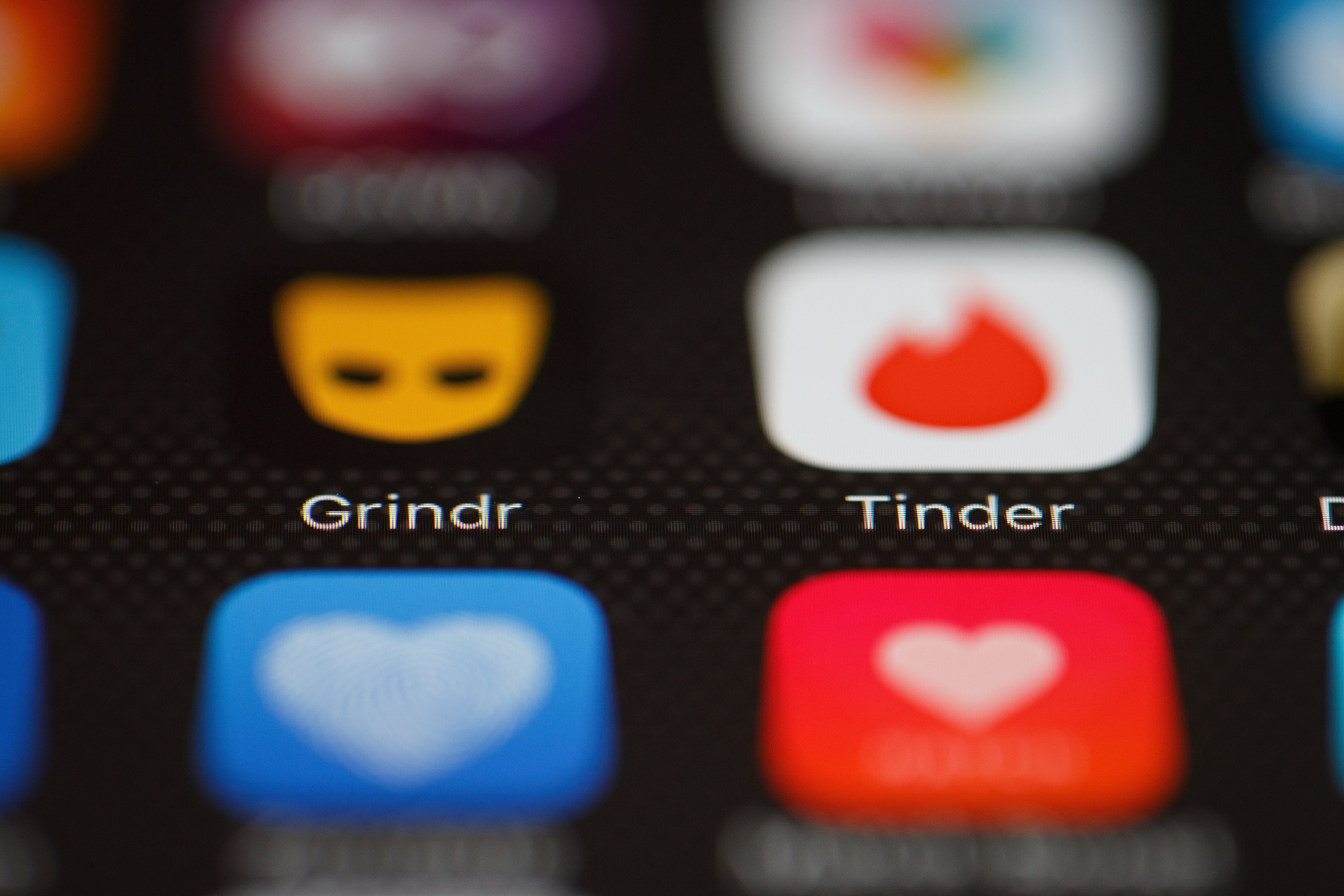 The Grindr and Tinder app logos are seen on a mobile phone scree