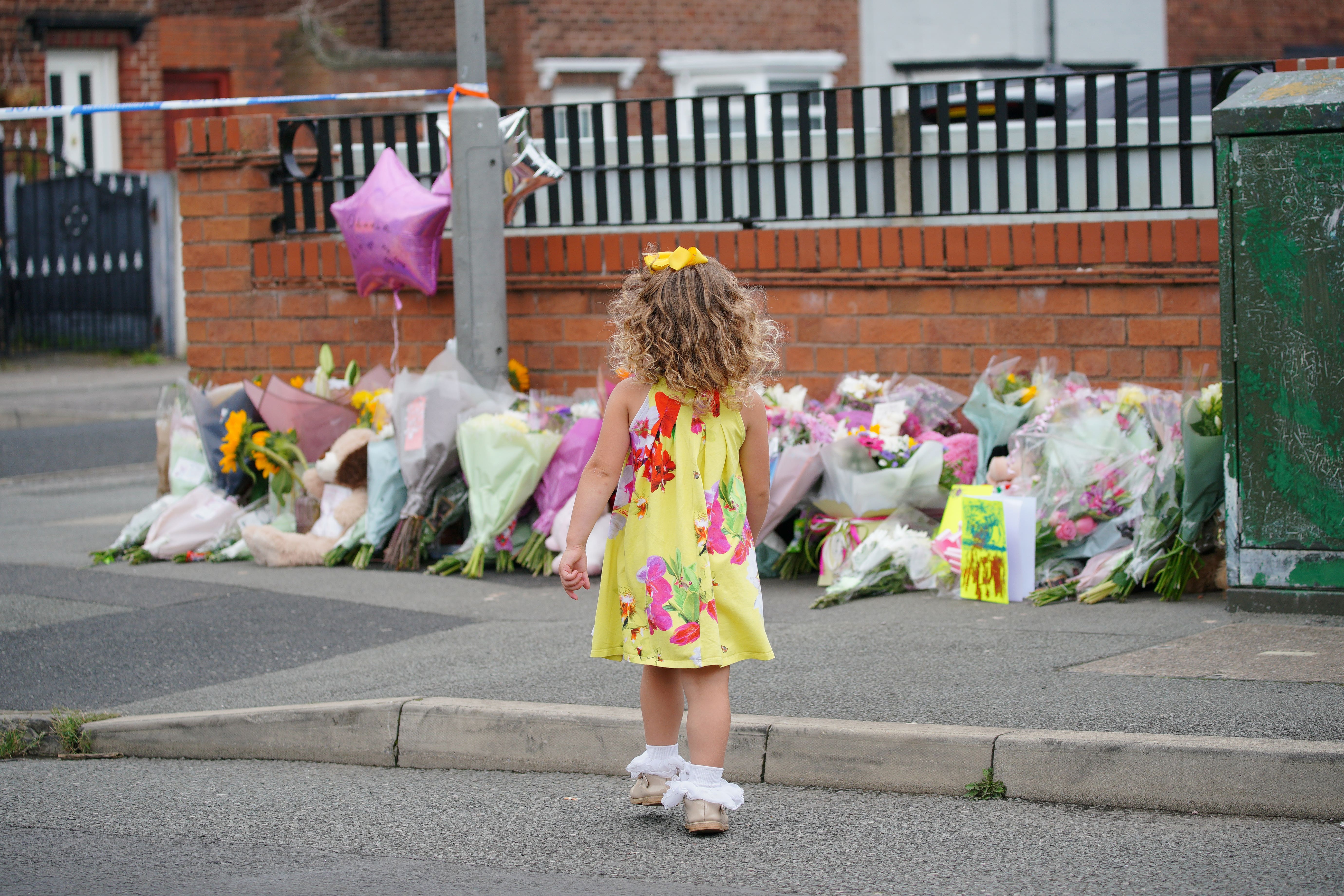 A young girl lays a tribute in Kingsheath Avenue, Dovecot, Liverpool