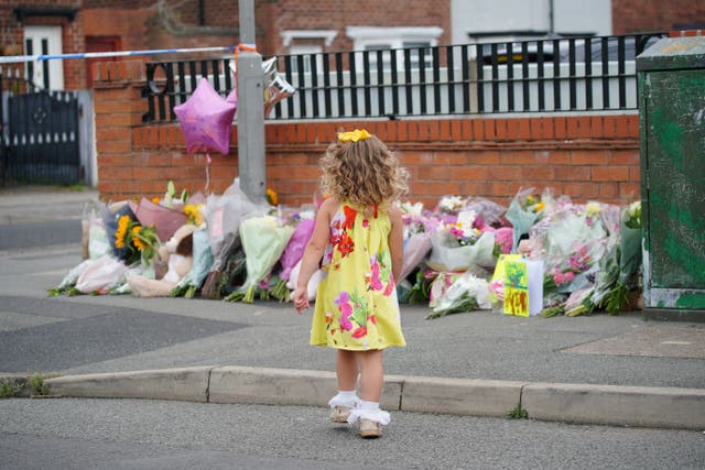 <p>A young girl lays a tribute in Kingsheath Avenue, Dovecot, Liverpool (Peter Byrne/PA)</p>
