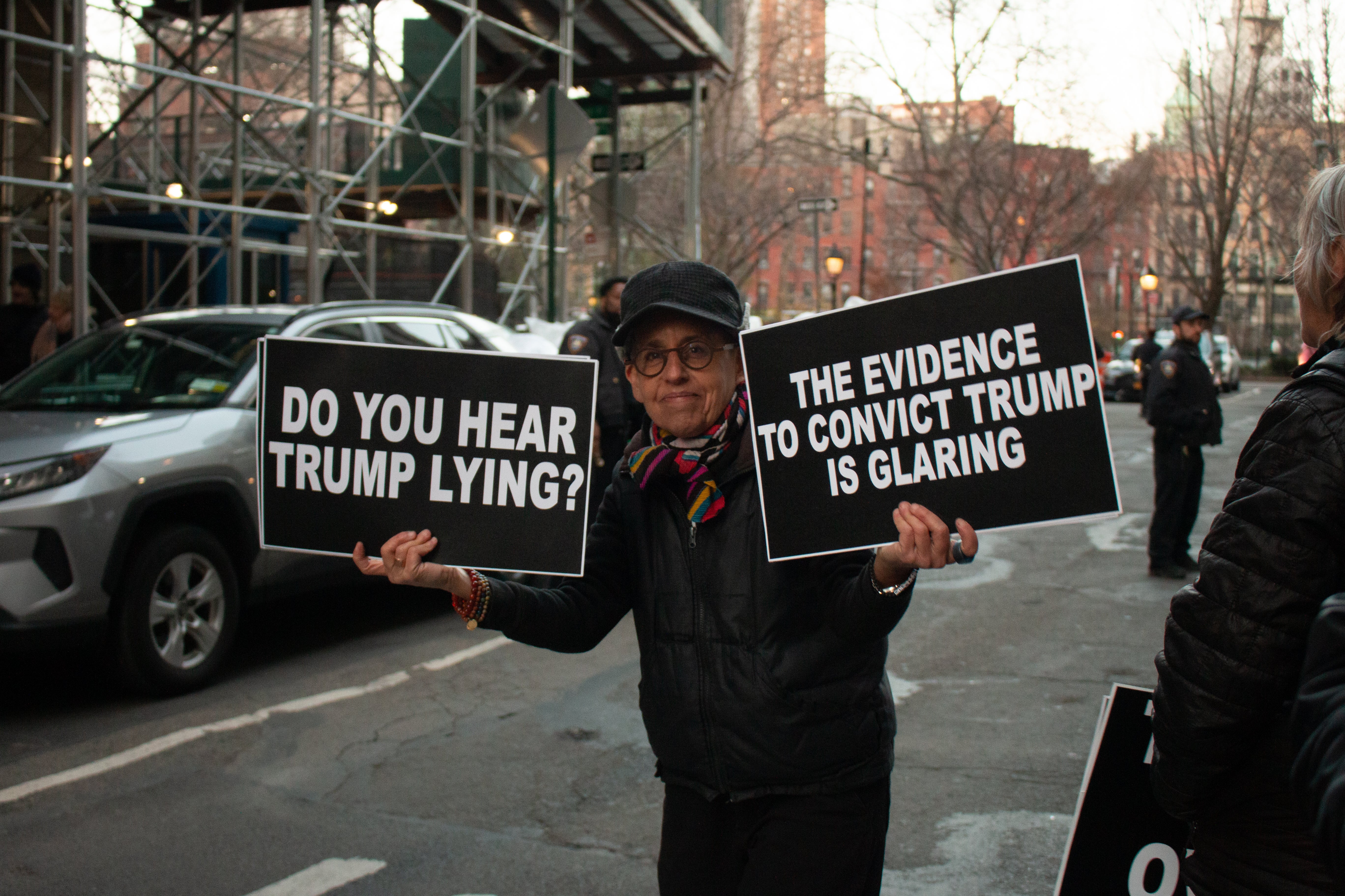 A protester holds up signs in support of the Trump indictment