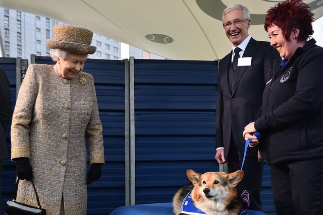 <p>Queen Elizabeth II looking at a Corgi as Paul O’Grady looks on during a visit to Battersea Dogs and Cats Home in London in 2015</p>