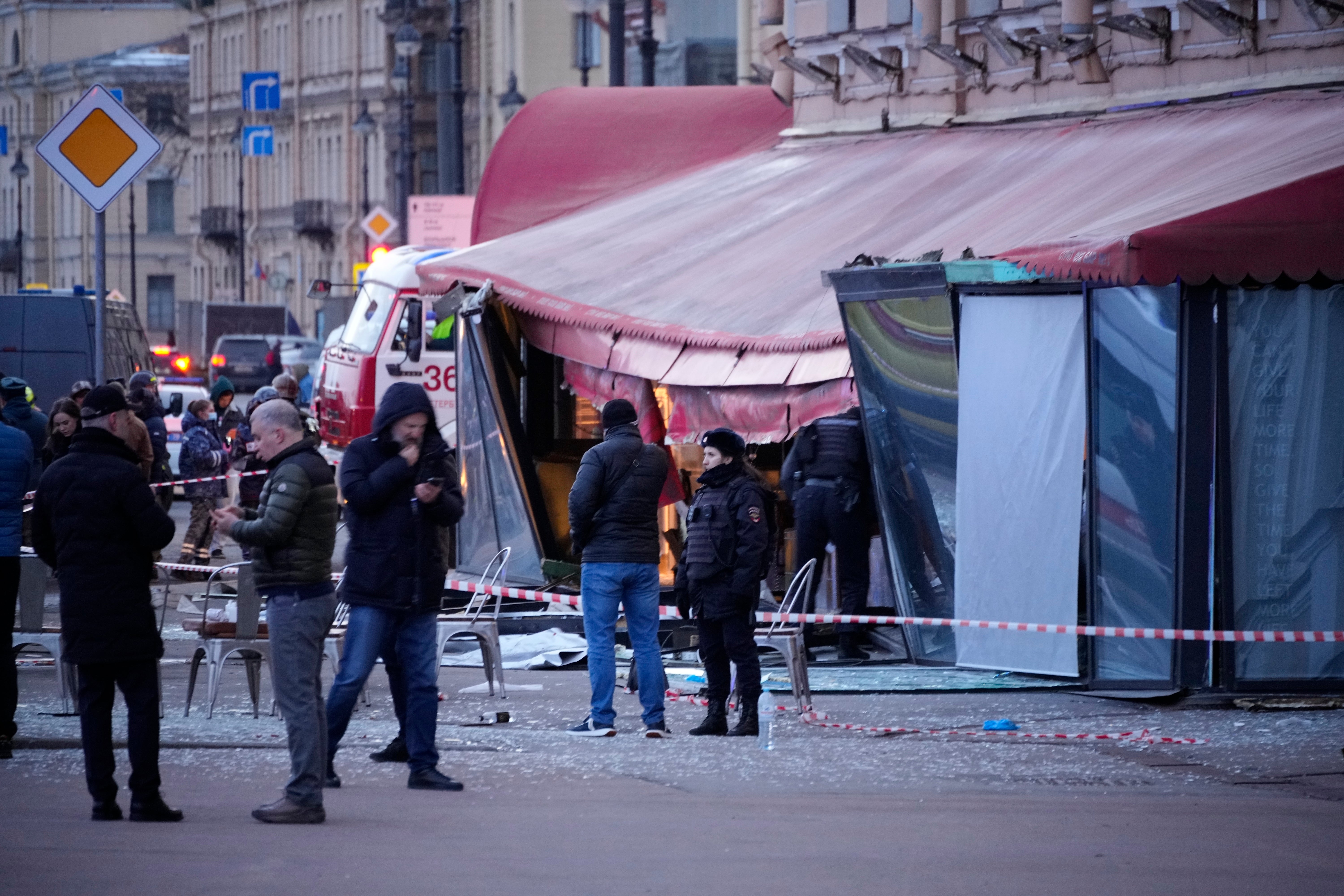 Russian investigators and police officers stand at the side of an explosion at a cafe in St. Petersburg, Russia