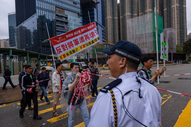 <p>Police watch protesters walking within a cordon line wearing number tags during a rally in Hong Kong</p>