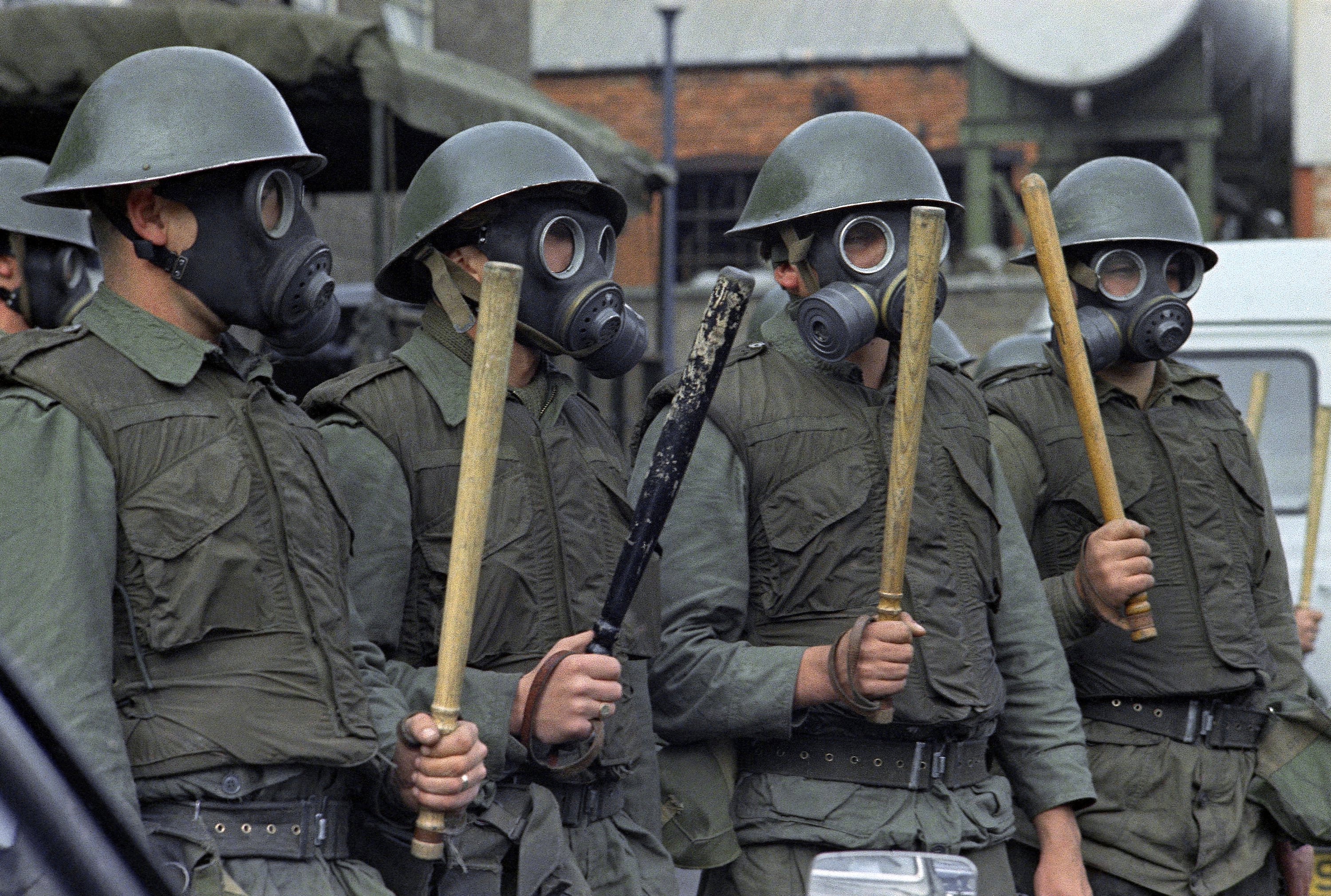 British Army Riot Squad troops wearing gas masks, bullet proof vests and wielding two foot long batons in Belfast