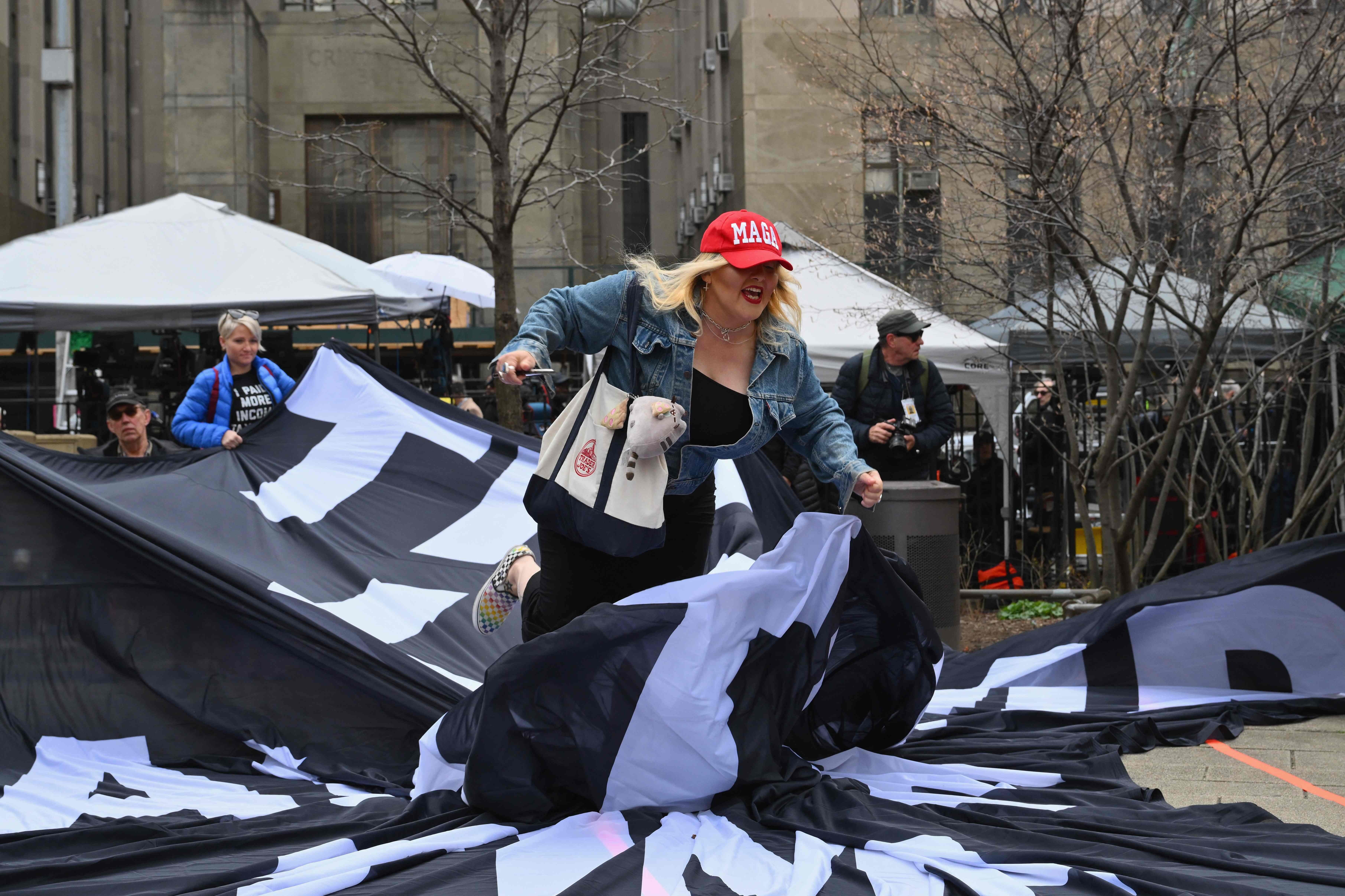 A supporter of former US president Donald Trump tears up an anti-Trump banner during a protest outside of Manhattan Criminal Court in New York City