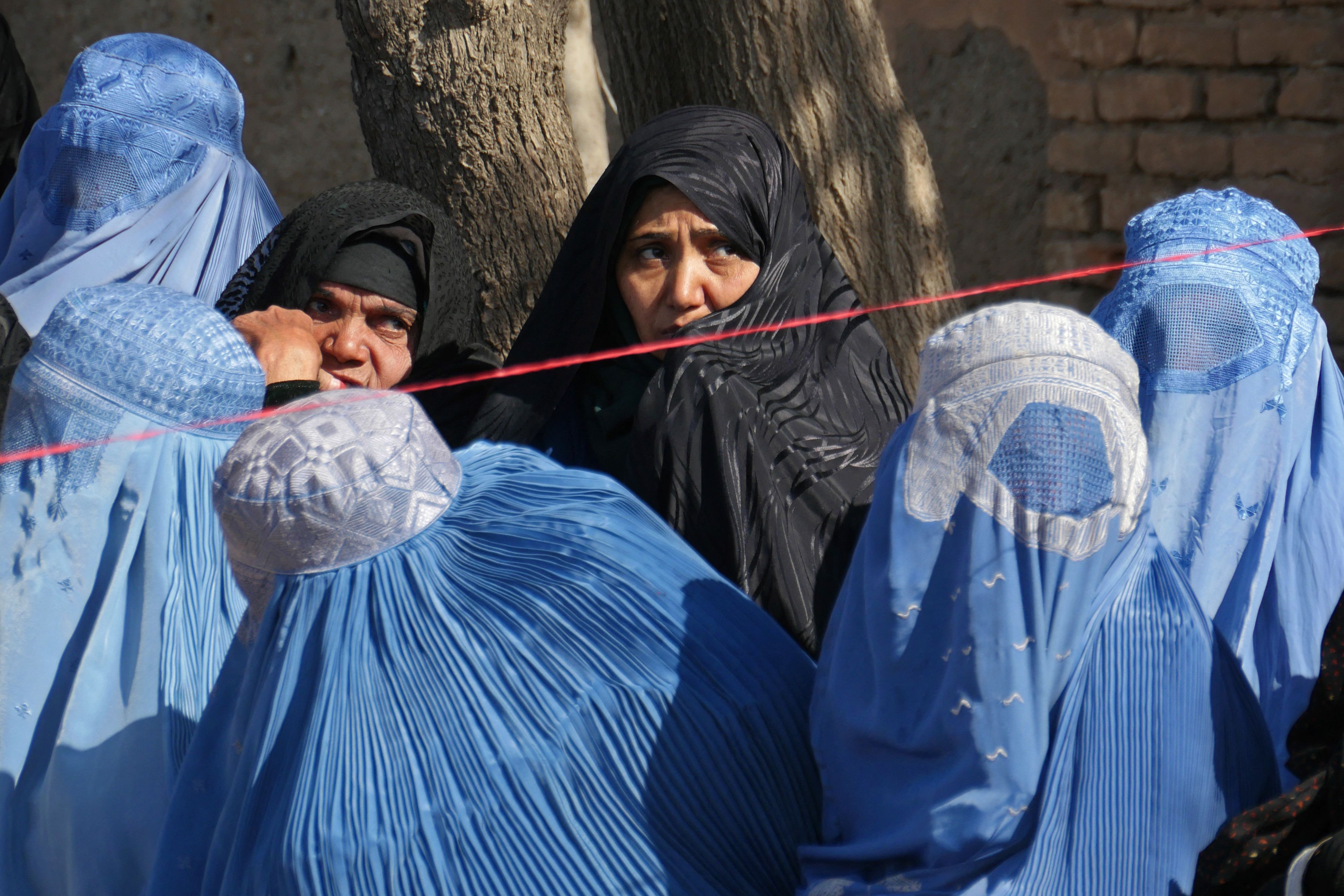 Afghan women wait to receive food aid from the Afghanistan Disaster Management, in Herat