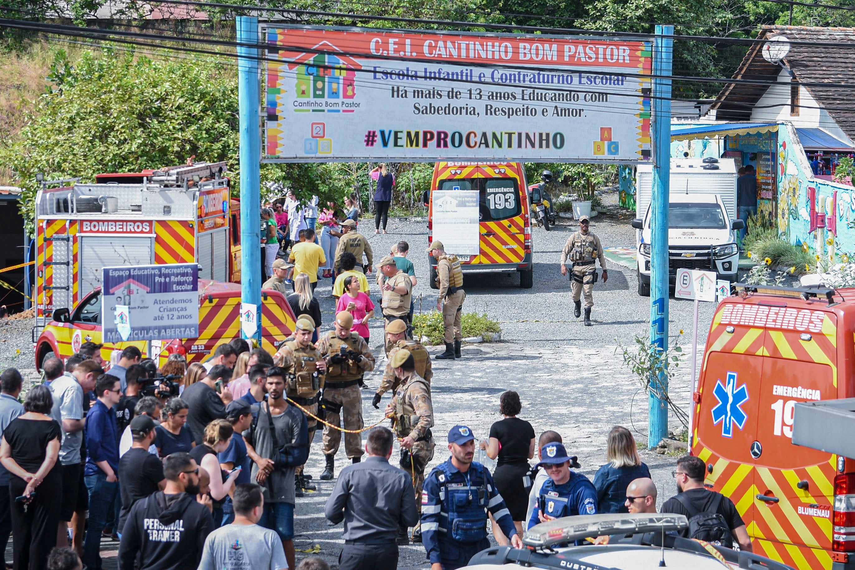 A crowd gathers as police and firefighters block the entrance to the Cantinho do Bom Pastor nursery